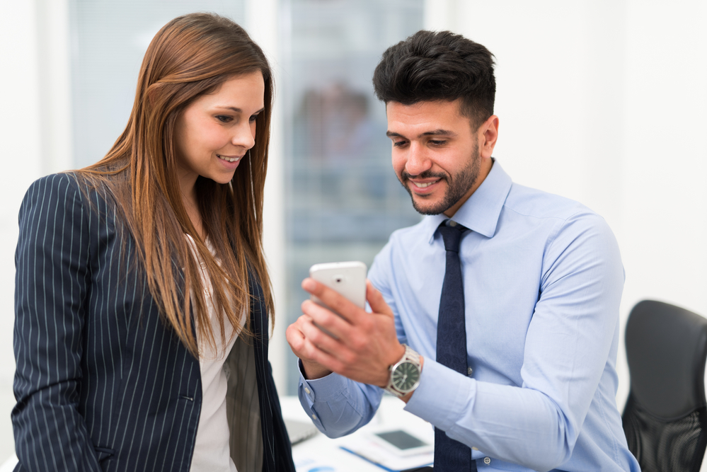 businessman showing businesswoman something on his phone